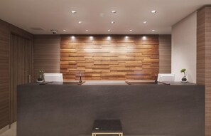 A reception desk with a wooden panel wall, two receptionists' stations, and a small step leading to the desk. - Jr-east Hotel Mets Urawa (Saitama)