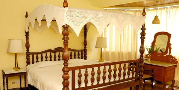 A four-poster bed with a canopy, two bedside lamps, a wooden dresser, and a mirror. - Windsor Hotel (Nuwara Eliya)