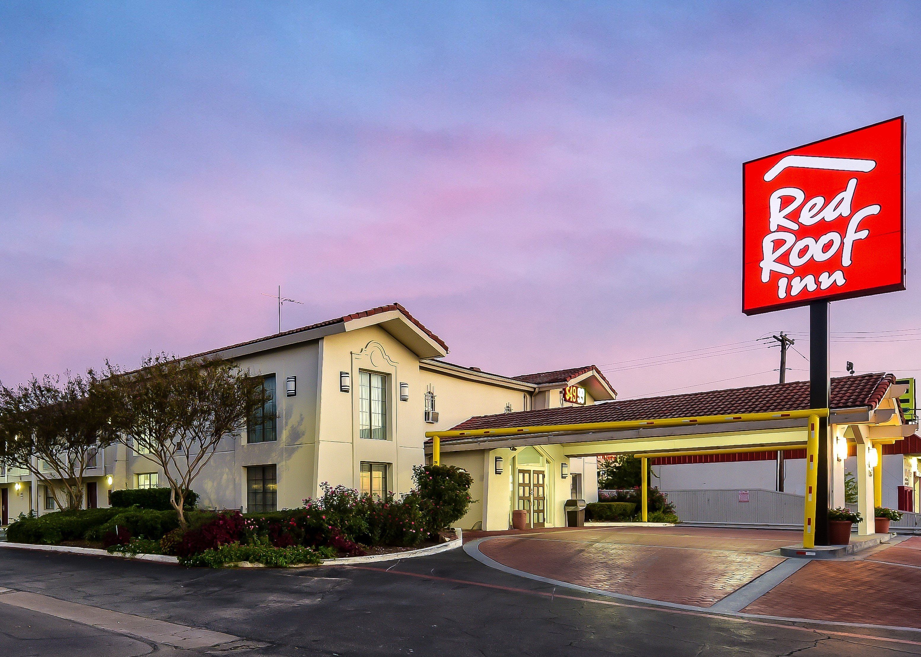 A Red Roof Inn with a covered entrance, a clear sky, and a well-maintained exterior.