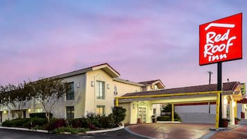 A Red Roof Inn with a covered entrance, a clear sky, and a well-maintained exterior.