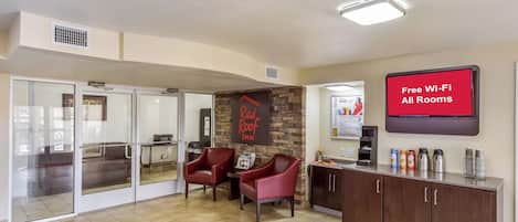 Un vestíbulo de hotel con mostrador de recepción, zona de estar e indicación de Wi-Fi gratuito en todas las habitaciones.