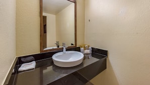 A bathroom with a white sink, black countertop, and a large mirror. - Red Roof Inn Plano (Plano)