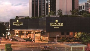 A modern hotel with a distinctive cylindrical tower and a flat-roofed entrance. - Shangri-la Hotel (Shenzhen)