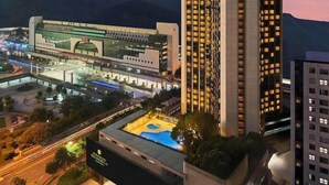 A modern hotel with a prominent tower, a large parking area, and a well-lit entrance. - Shangri-la Hotel (Shenzhen)