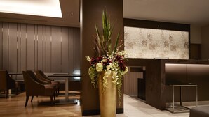 Un vestíbul modern amb un ampli arranjament floral, zona de seients i una recepció.