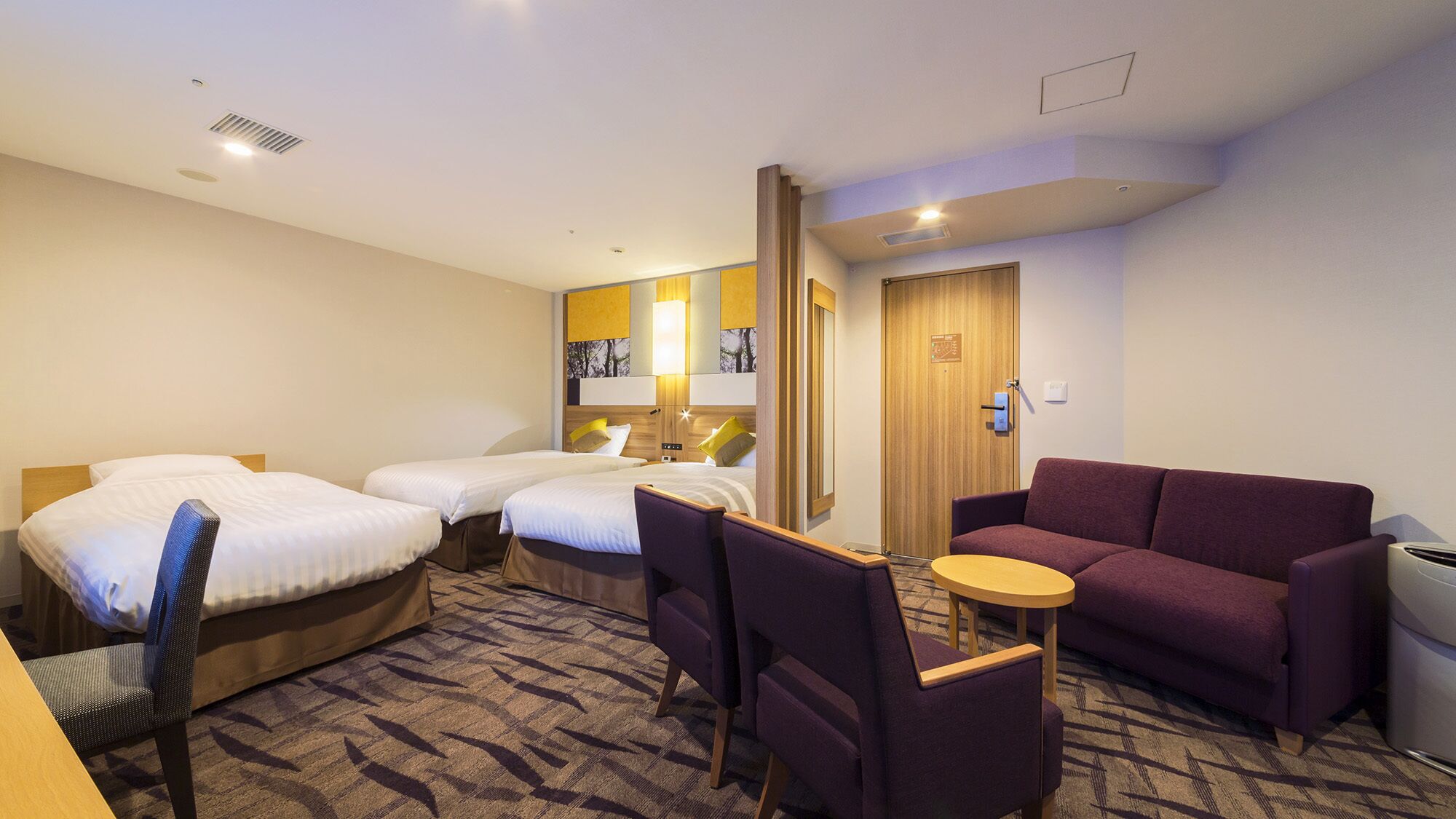 Habitación de hotel con dos camas, un sofá, una mesita y una silla.