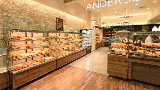 Una fleca amb diverses vitrines plenes de productes de forneria, una paret de maó i el nom 'ANDERSEEN' ben visible.