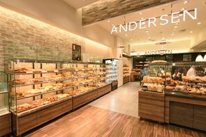 Une boulangerie dotée de plusieurs vitrines remplies de produits de boulangerie, d’un mur en briques et du nom « ANDERSEEN » affiché en évidence.