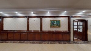 Un pasillo con un banco de madera, un cuadro enmarcado y una puerta con paneles de vidrio.