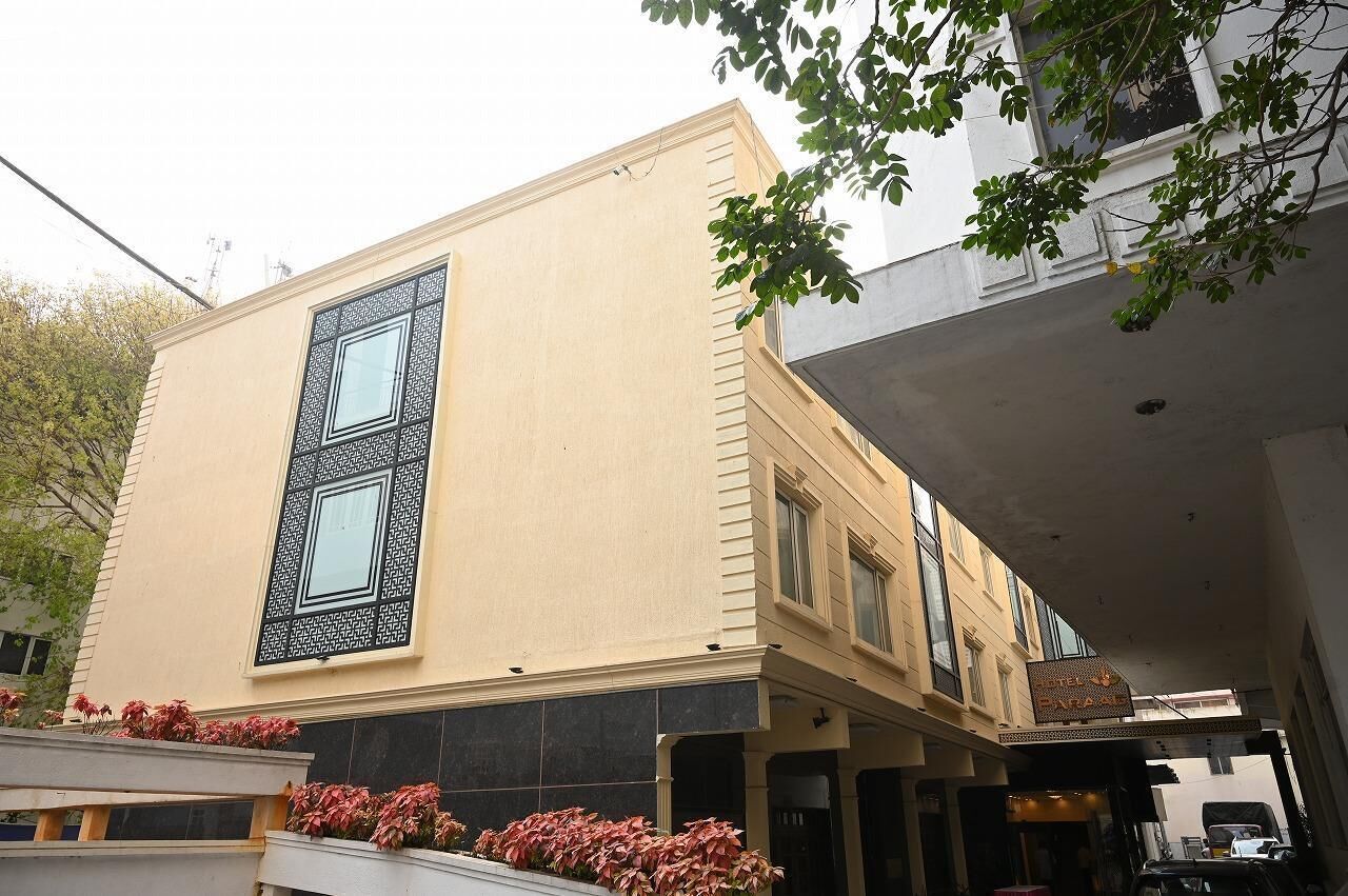 Un immeuble à la façade beige, doté d’une grande fenêtre décorative et d’une enseigne indiquant « Hôtel Paralle ».