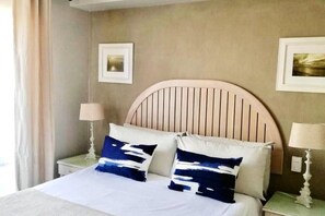 A hotel room with a bed, two bedside tables, and two lamps.