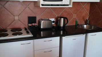 A compact kitchen with a gas stove, a microwave, a toaster, and a sink.