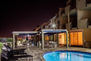 An outdoor pool area with lounge chairs, a covered seating area, and a building with balconies. - Leisure Bay (Cape Town)
