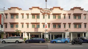 A pink hotel with a sign reading "Amrice Hotel". There are cars parked in front and a motorcycle on the street. - Amrise Hotel (SINGAPORE)