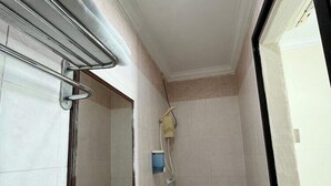 A bathroom with a white sink, a mirror, a towel rack, and a shower area. - Amrise Hotel (SINGAPORE)