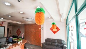 A reception area with a check-out counter, a leather sofa, and decorative pineapple ornaments. - Amrise Hotel (SINGAPORE)