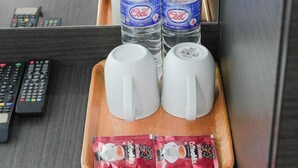 A tray with two white mugs, two bottles of water, and two packets of coffee mix on a wooden tray. - Amrise Hotel (SINGAPORE)