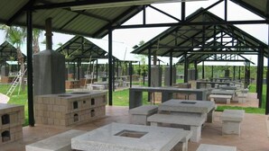 Un pabellón al aire libre con bancos de piedra y una chimenea central.