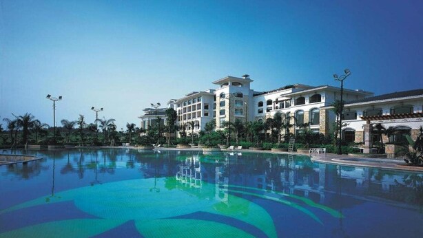 Una piscina grande con el reflejo de un edificio hotelero de varios pisos.