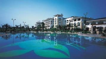 A large swimming pool with a reflection of a multi-story hotel building.