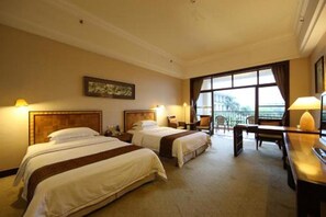 Habitación de hotel con dos camas, un escritorio y un ventanal grande.