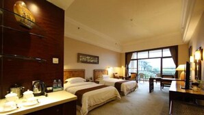 Una habitación de hotel con dos camas, un escritorio y un ventanal grande.