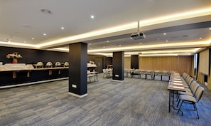 A conference room with a long table and chairs, a buffet area with covered dishes, and a projector on the ceiling. - Capetonian Hotel (Cape Town)