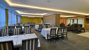 A dining area with tables set for service, chairs, and a seating area with sofas and armchairs. - Capetonian Hotel (Cape Town)