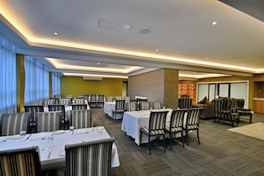 A dining area with tables set for service, chairs, and a seating area with sofas and armchairs. - Capetonian Hotel (Cape Town)
