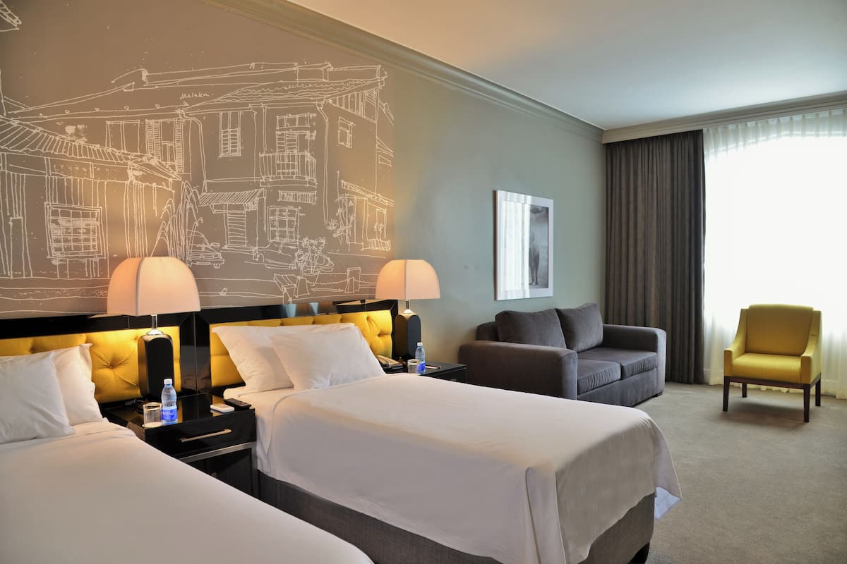 A hotel room with two beds, a sofa, a chair, a wall mural, and a window with curtains.