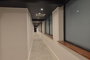 A long, narrow hallway with a tiled floor, recessed lighting, and large windows on one side. - Capetonian Hotel (Cape Town)