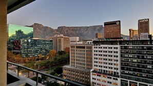 A cityscape with modern buildings, including a prominent EXL building and a Luno building, with mountains in the background. - Capetonian Hotel (Cape Town)