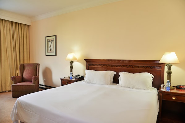 A hotel room with a large bed, two bedside tables, a chair, a lamp, and a framed picture on the wall. - Capetonian Hotel (Cape Town)