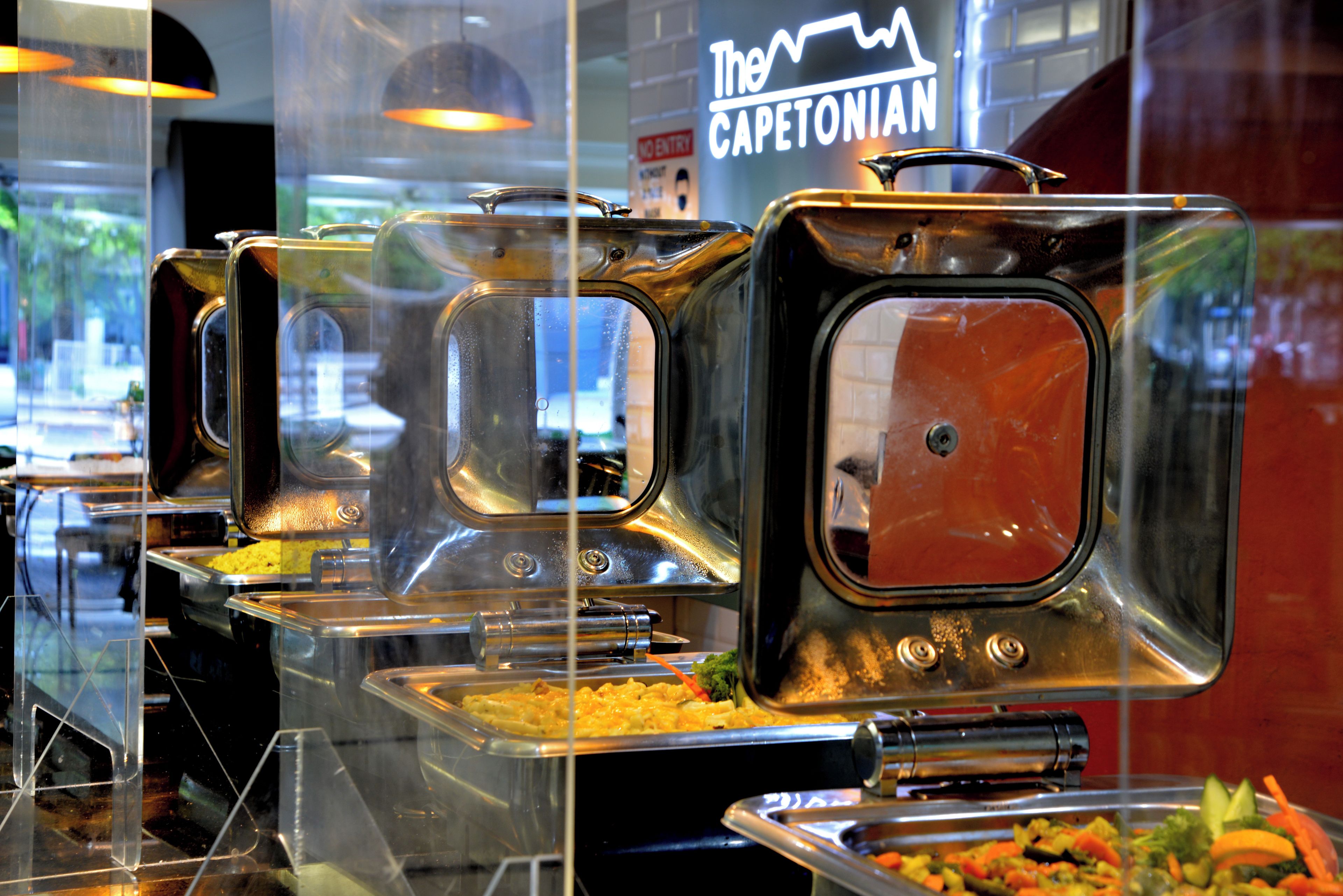 A buffet with multiple serving stations, each with a covered food container.