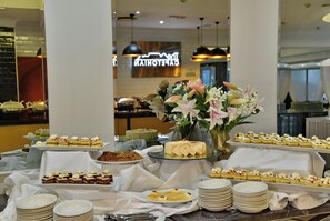 A buffet table with various desserts and a floral centerpiece.