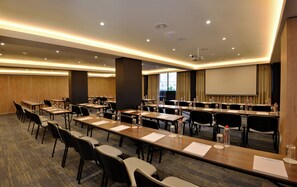 A conference room with long tables, chairs, water bottles, and a projector screen. - Capetonian Hotel (Cape Town)