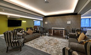 A modern living room with a sectional sofa, striped armchairs, a coffee table, and a patterned rug. - Capetonian Hotel (Cape Town)
