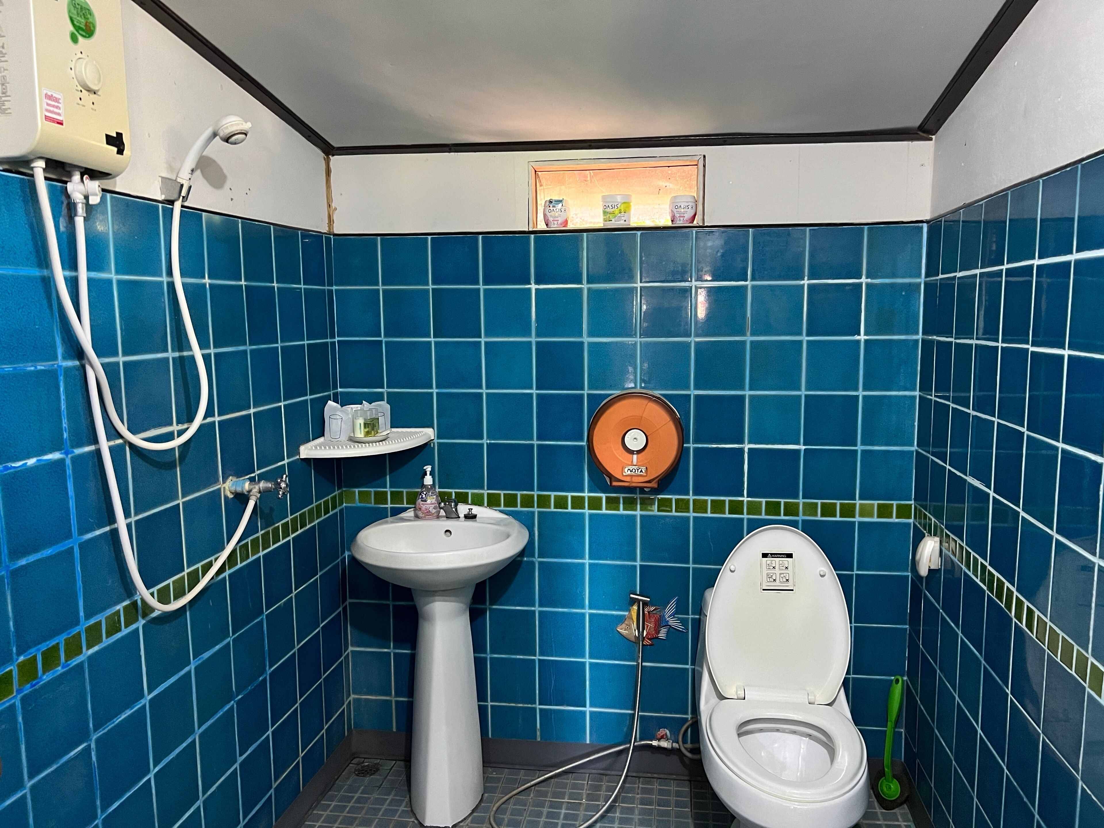 Un baño con azulejos azules, un lavabo blanco, un inodoro y una ducha.