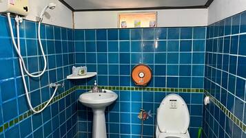 Un baño con azulejos azules, un lavabo blanco, un inodoro y una ducha.