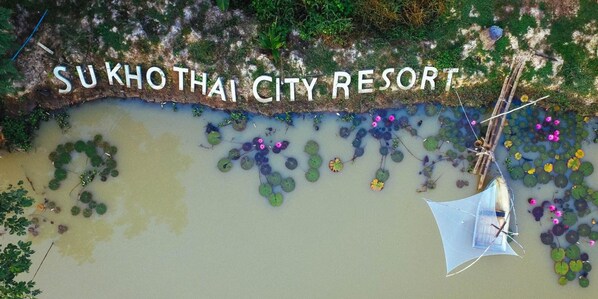 An aerial view of Su Kho Thai City Resort with a water body, floating plants, and a small boat. - Sukhothai City Resort (Sukhothai)