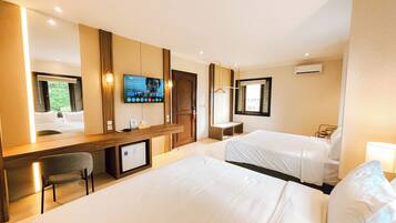 Habitación de hotel con cama, escritorio, silla, televisor y ventana.