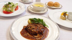 A table set with various dishes including a salad, soup, and meat with sauce. - Kyu Karuizawa Hotel Shinonome (Karuizawa)