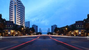 A modern hotel with a distinctive chevron-shaped tower, a well-lit facade, and a spacious entrance area. - Haitian Hotel (Kunming)