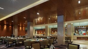 A hotel dining area with multiple tables set for guests, a bar area, and a reception desk. - Haitian Hotel (Kunming)