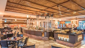 Un restaurant doté d’un plafond en bambou, de murs en briques apparentes et d’un espace buffet proposant une variété de plats.