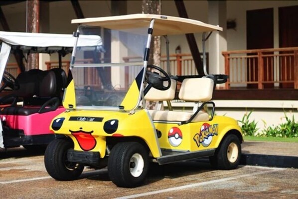 A yellow golf cart with a Pokemon theme parked on a paved area. - Nirwana Beach Club (Bintan)