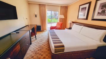 A hotel room with a bed, a desk, a chair, a television, and a window with curtains.