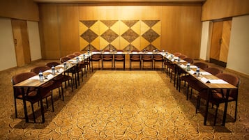 A conference room with a long table, chairs, and a patterned carpet.