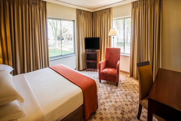 A hotel room with a bed, a television, a chair, and a table. - Garden Court Ulundi (Ulundi)