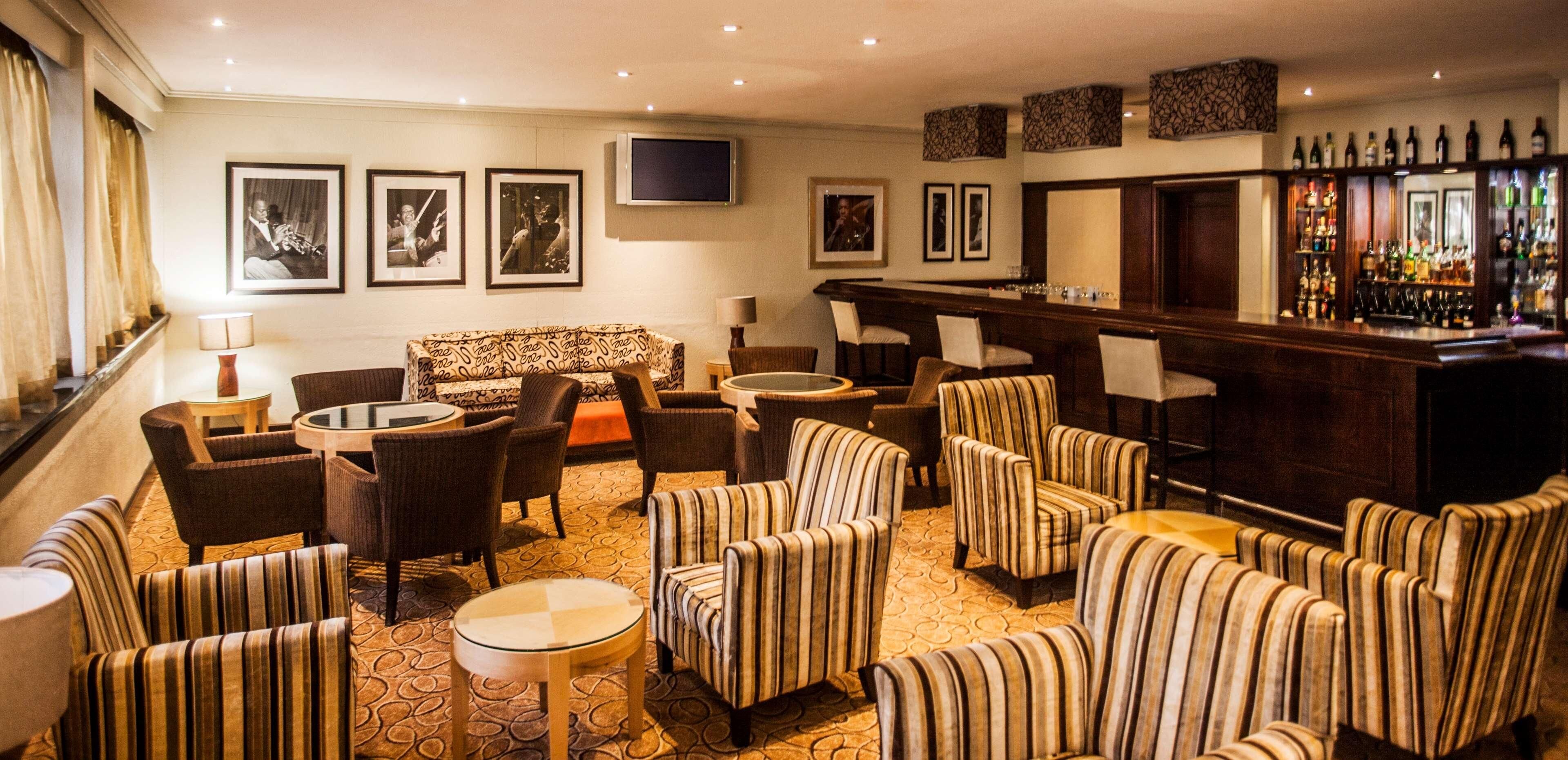 A bar area with a long counter, multiple chairs, a sofa, and a television mounted on the wall.
